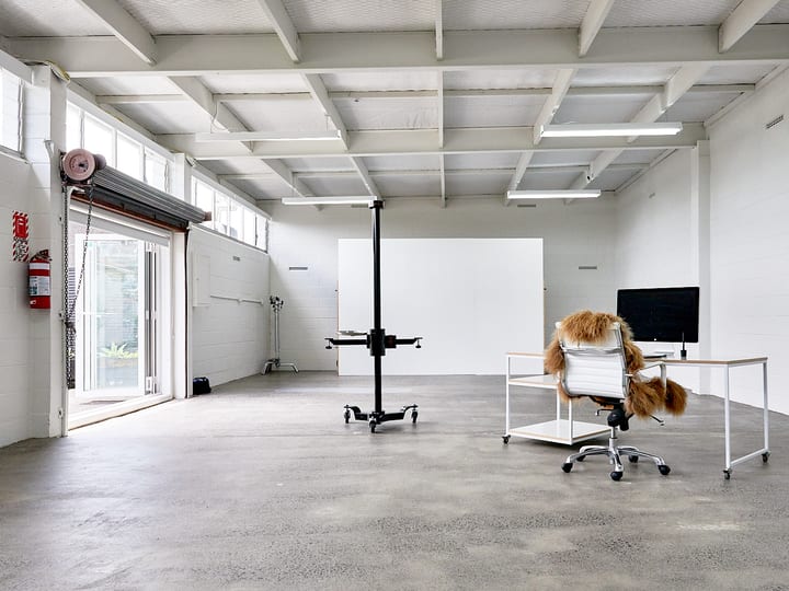 Open white industrial space with concrete floor, photography backdrop and desk