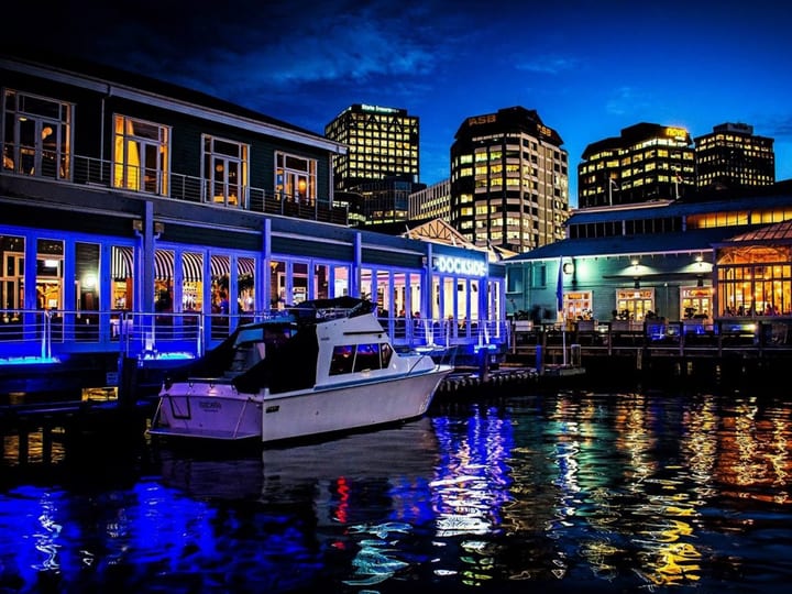 Dockside and city waterfront at night with blue lighting and a moored boat
