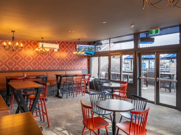 Bar dining room with red patterned wallpaper, leather booths and chandelier