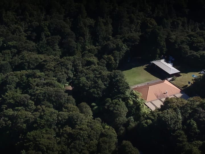 Aerial view of lodge buildings and lawn clearing in forest setting