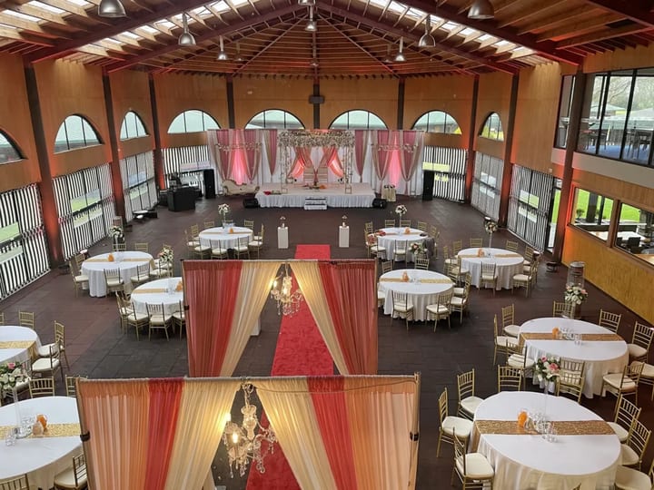 High-vaulted timber pavilion set for a large reception with round tables and coloured draping