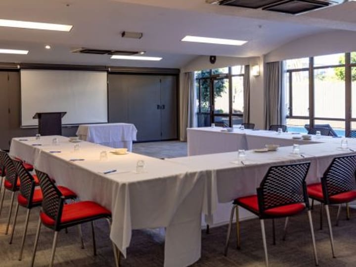 Conference room with classroom seating layout, projector screen and garden-view windows