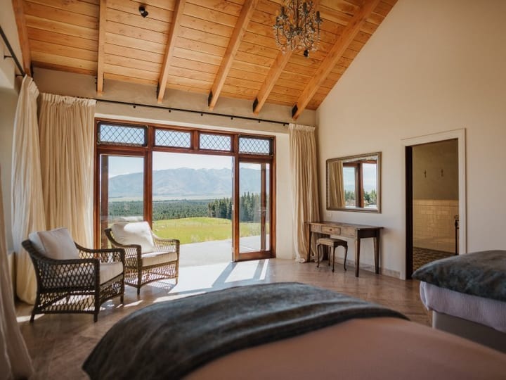 Bedroom with timber ceiling and glazed French doors open to mountain view