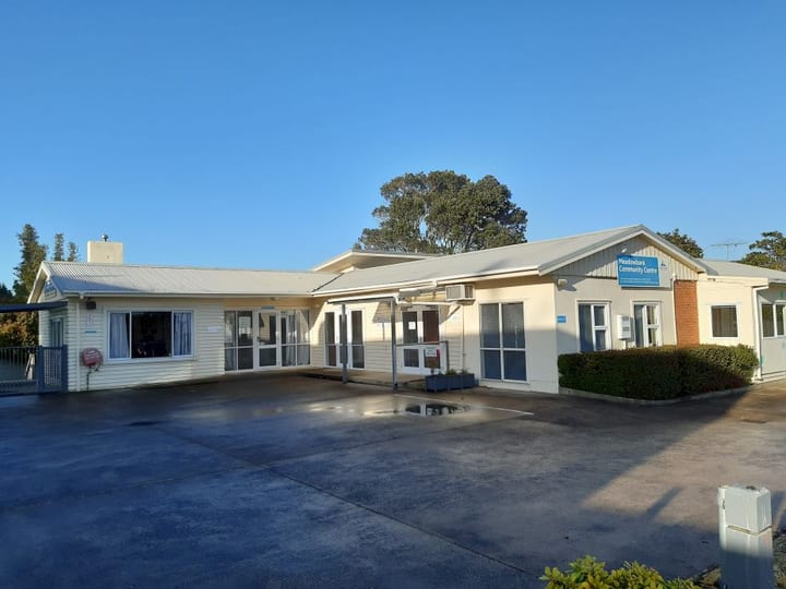 Single-storey community centre building with carpark in morning light