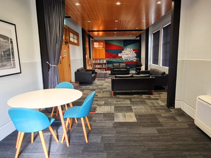 Open lounge area with sofas, round table, and colourful mural with bookshelf