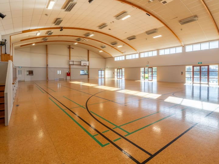 Large sports hall with curved timber roof and polished floor