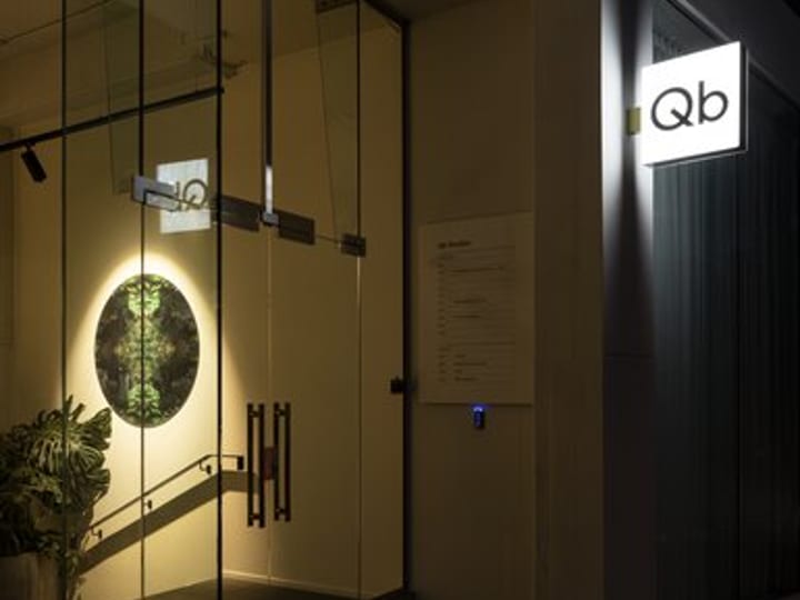 Illuminated glass entry at night with Qb signage on dark building facade