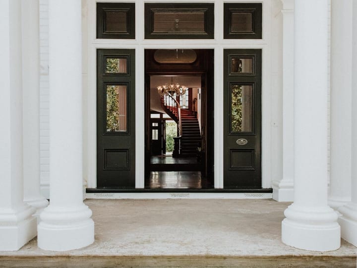White columned portico with open double doors revealing interior staircase