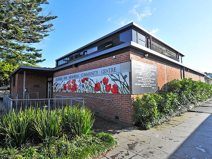 Brick community centre showing side elevation with poppy mural and garden planting