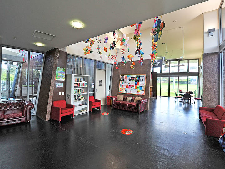 Foyer with dark polished floor, red seating, bookshelves, and hanging decorations