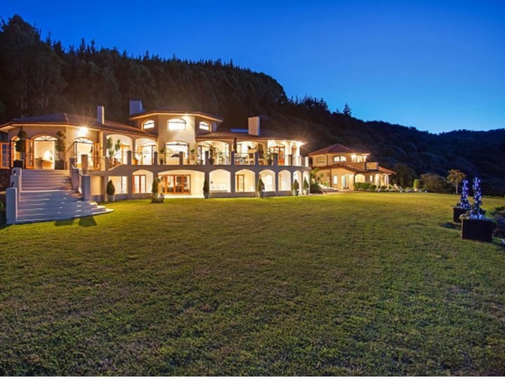 Mediterranean-style two-storey venue lit at night with arched colonnades against dark hills