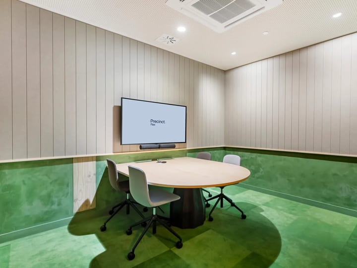 Small meeting room with round-ended table, grey chairs, screen and vertical timber wall panelling