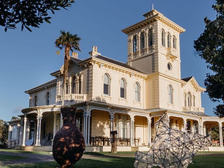 Large cream Victorian Italianate homestead with tower, wide verandah and columns, sculptures on lawn