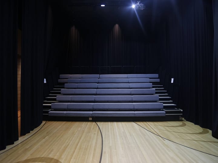 Retractable bleacher seating in a dark-draped performance space with timber floor