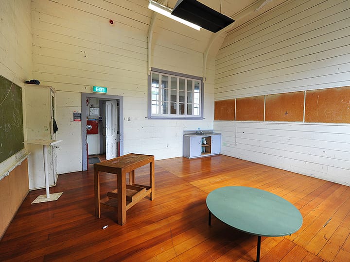 Plain hall interior with timber floor, arched timber ceiling, and small tables