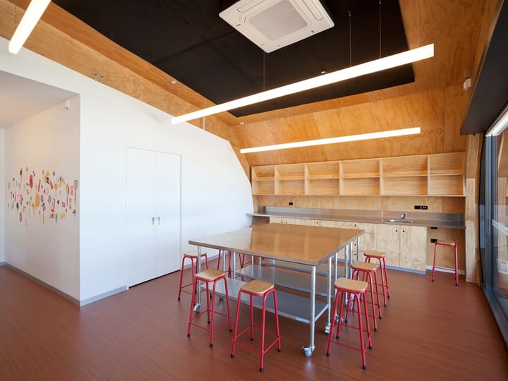 Studio room with plywood ceiling, red stools and built-in shelving