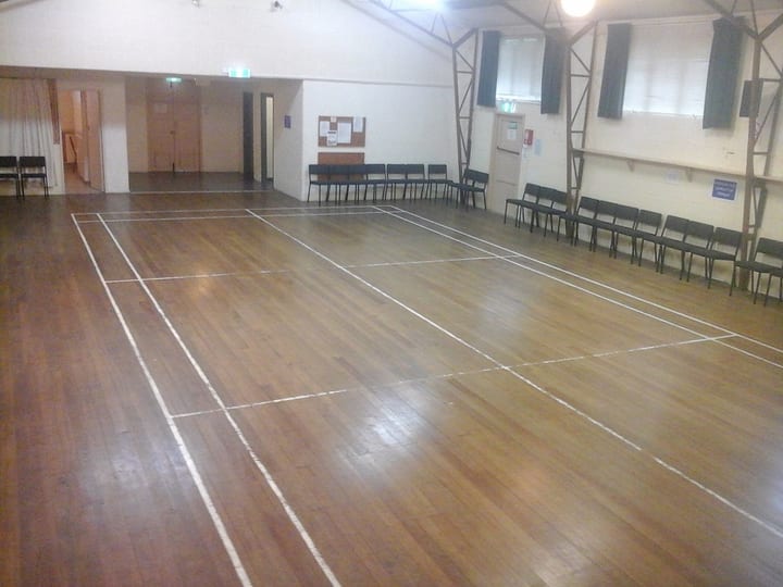 Large timber-floored hall with chairs along walls and court markings
