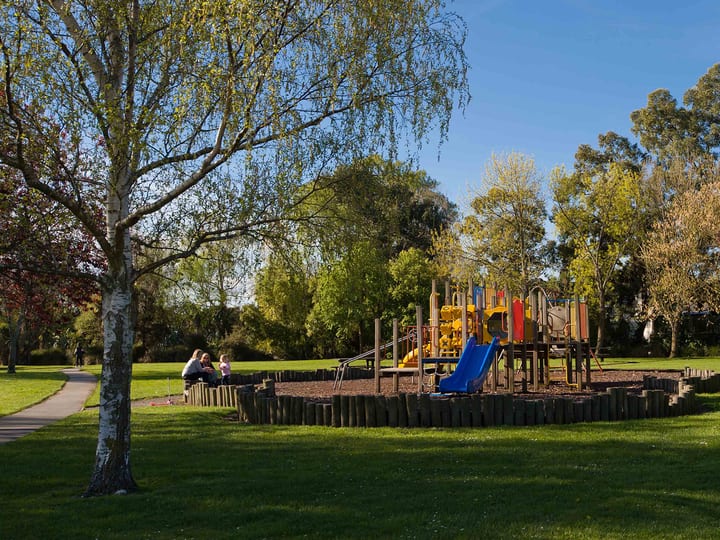 Playground with colourful equipment on a grass park with trees