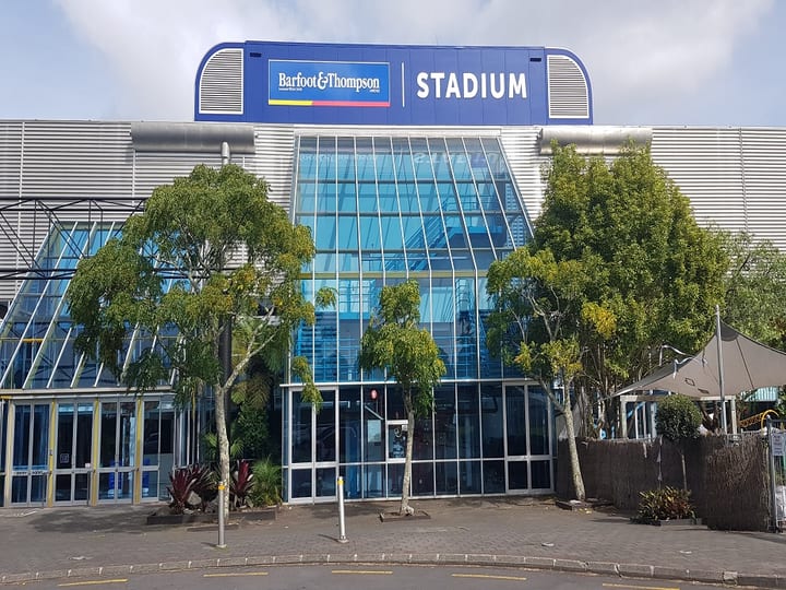 Stadium building facade with large glazed entrance and branded signage above