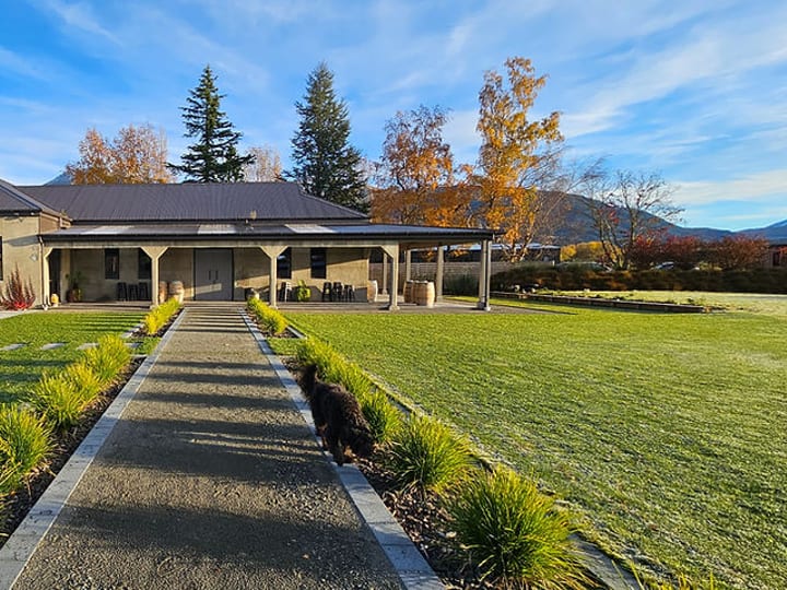 Single-storey rendered venue building with covered veranda, gardens, and mountain backdrop