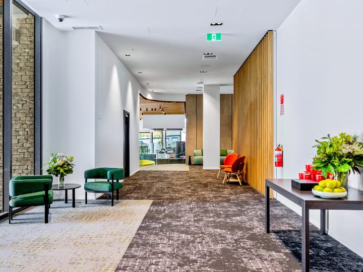 Contemporary foyer corridor with stone wall, timber slat partition, and colourful lounge chairs