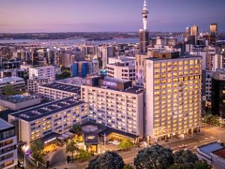Aerial dusk view of large multi-storey city hotel with illuminated tower and surrounding urban skyline