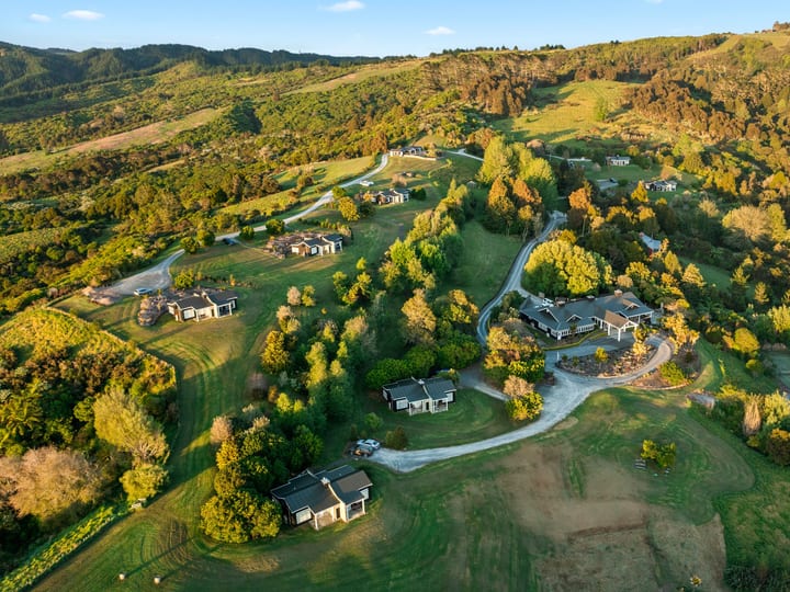 Aerial view of scattered dark-roof lodges across rolling green hills and woodland
