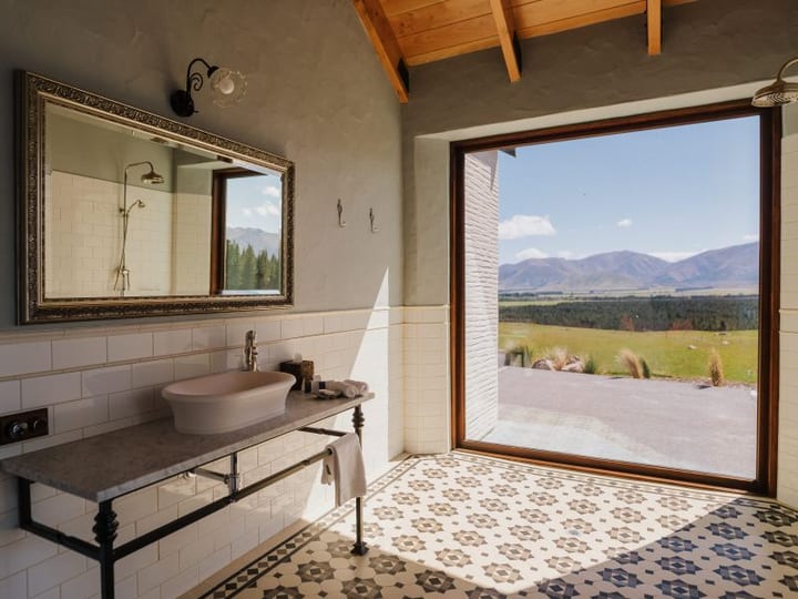Bathroom with patterned tile floor, vessel basin and large picture window to mountain plains