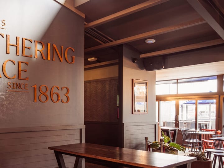 Pub bar area with branded mural wall, timber tables and booth seating
