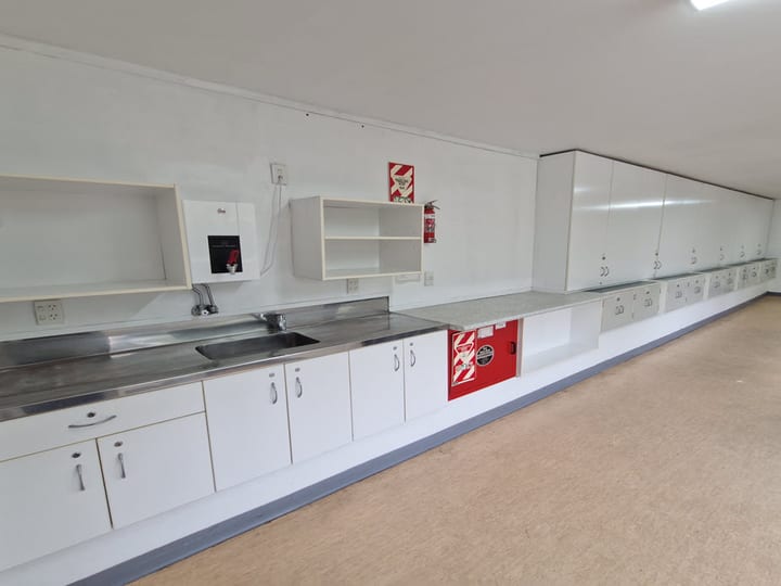 Small plain room with wall storage cabinets and a few stacked chairs