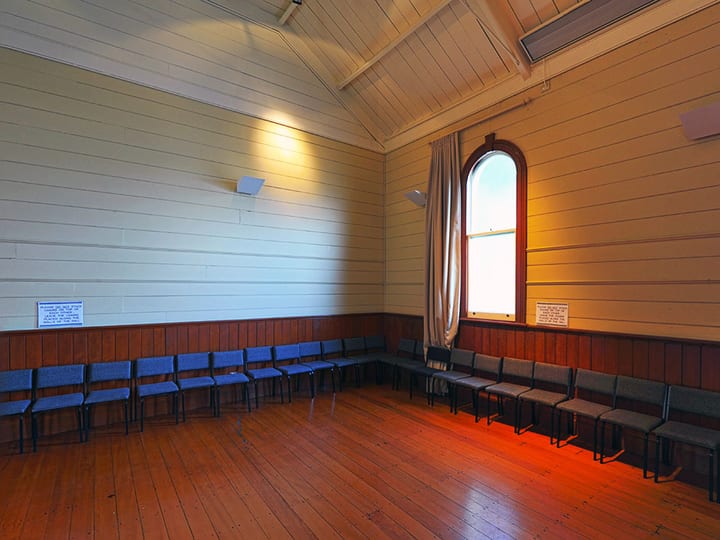 Timber-lined hall interior with arched window, wood-panelled dado, and polished floor