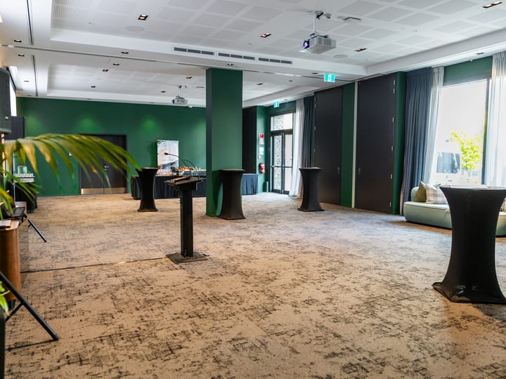 Large event space with green accent walls, standing tables and folding partition doors