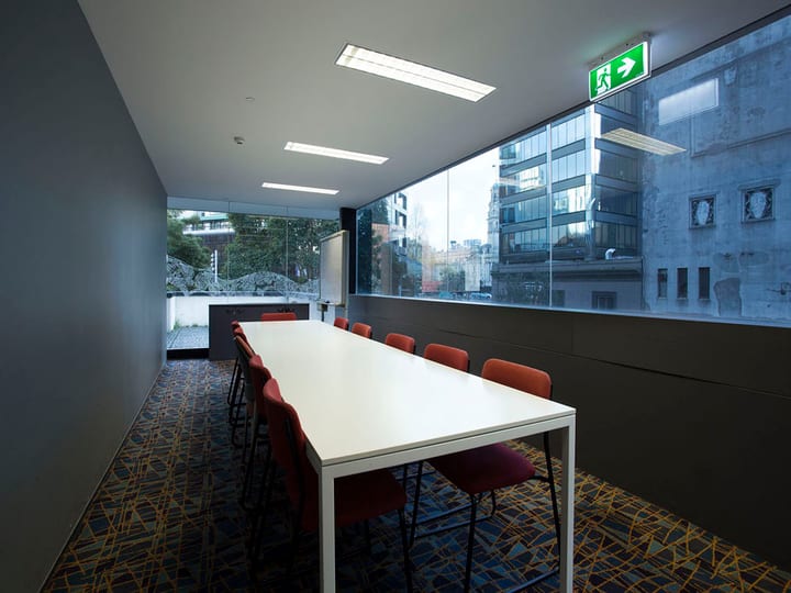 Narrow meeting room with long white table, red chairs and floor-to-ceiling windows