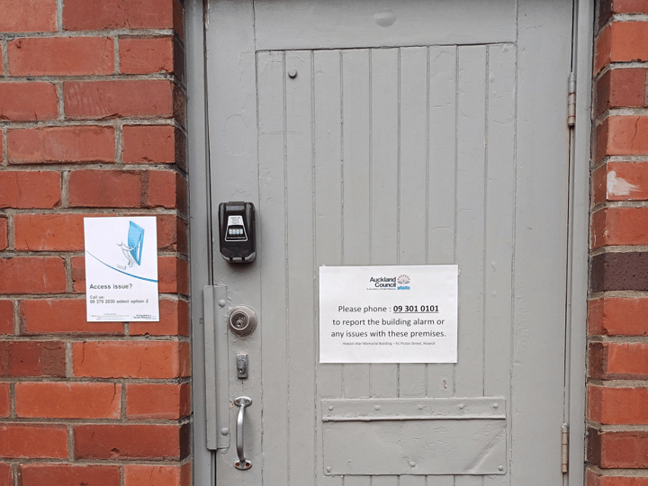 Close-up of grey door in brick wall with access control panel and council notices