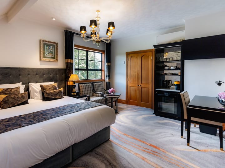 Hotel bedroom with chandelier, upholstered bedhead, and sitting area