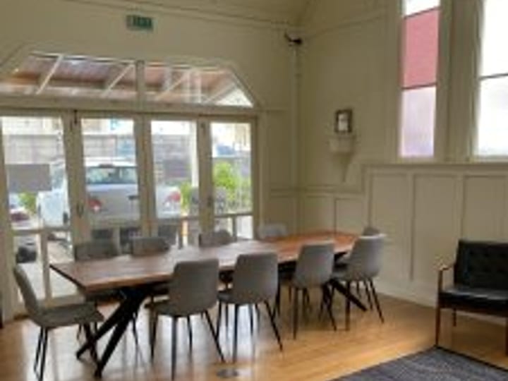 Room with arched windows, long dining table, upholstered chairs, and timber floor