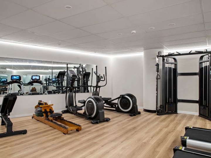 Hotel gym with cardio equipment, weight machines and mirrored wall