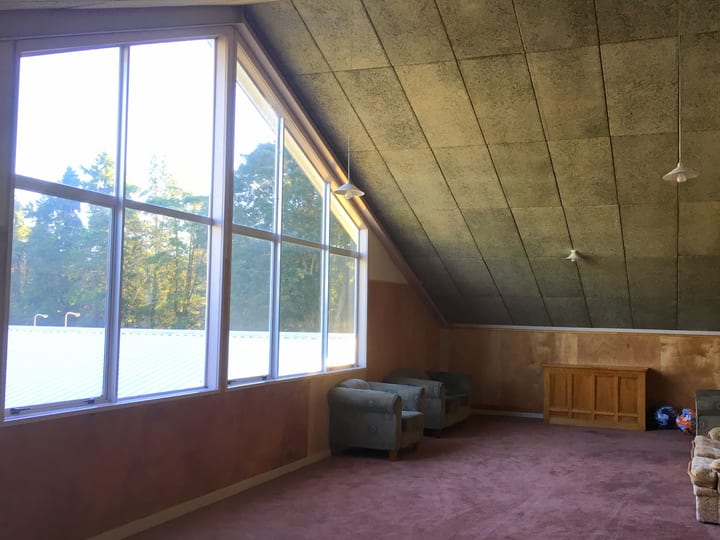 A-frame recreation room with large windows, armchairs and carpeted floor
