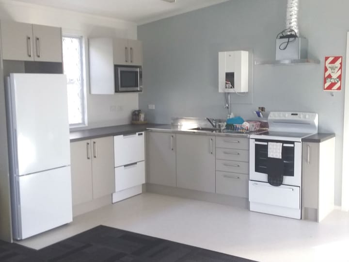 Compact kitchen with white cabinetry, fridge, stove and stainless sink