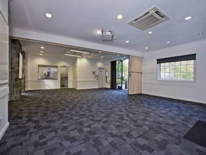 Open carpeted function room with projector and servery counter, folding partition visible