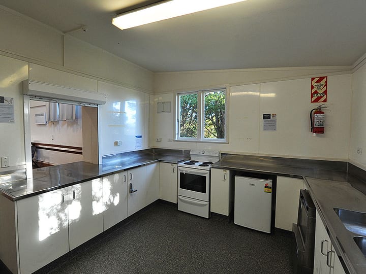 Community kitchen with white cabinetry, stainless benches and electric stove