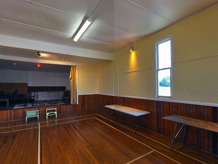 Plain rectangular hall with timber wainscoting, polished floorboards, and fluorescent lighting