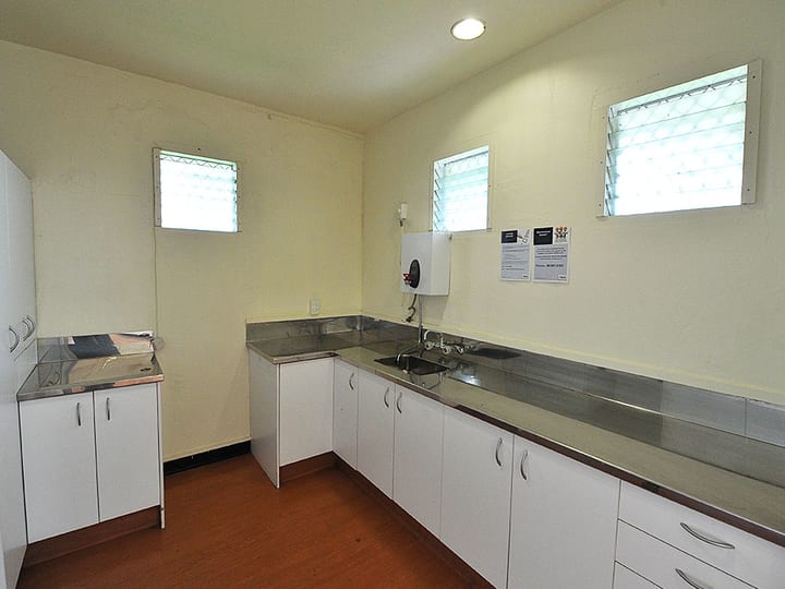 Compact kitchen with stainless benchtops, white cabinetry and louvre windows