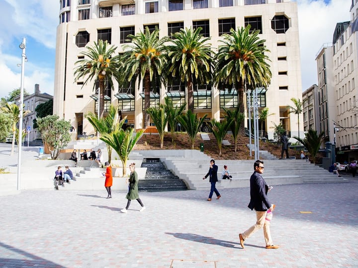 City plaza with trees, stepped seating and pedestrians outside the venue