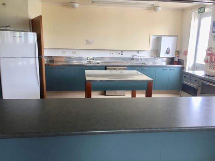 Hall kitchen with teal cabinetry, stainless bench and central island