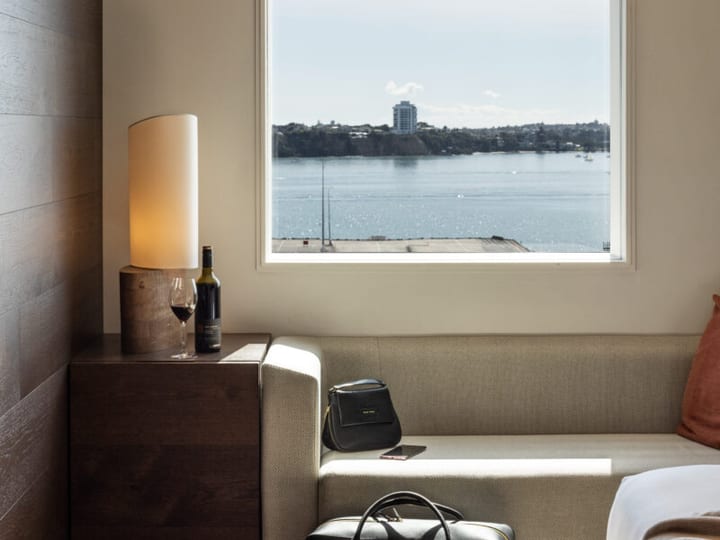 Hotel room corner with window seat, side table and lamp overlooking water
