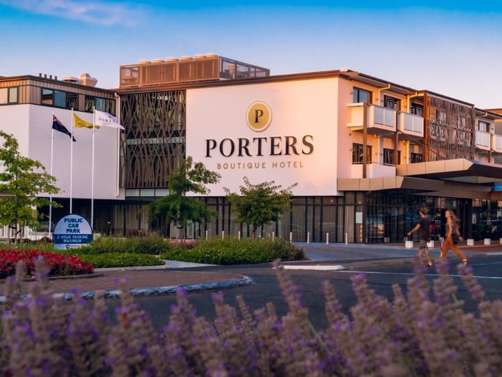 Contemporary multi-storey hotel with timber-screen facade, signage and landscaped forecourt at dusk