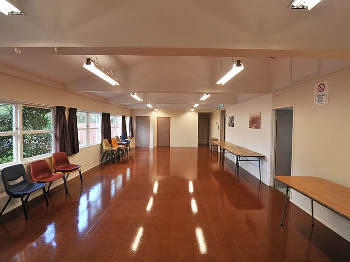 Plain rectangular hall with polished floor, chairs and long trestle table