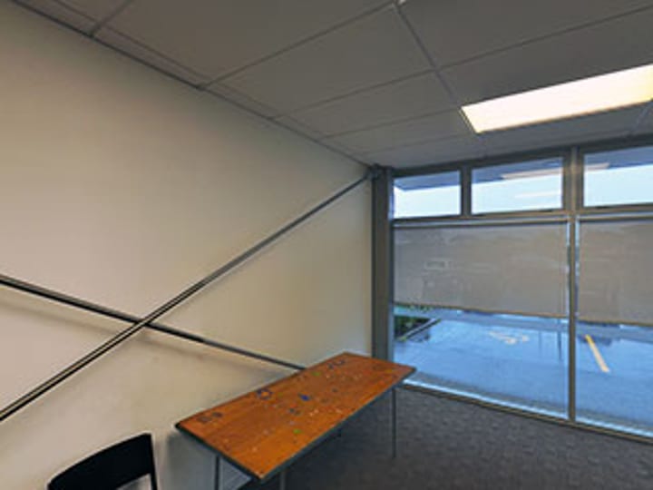 Small meeting room with bench desk, chairs and large window overlooking car park