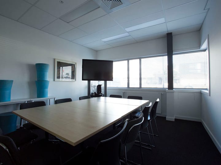 Meeting room with large table, chairs and wall-mounted screen